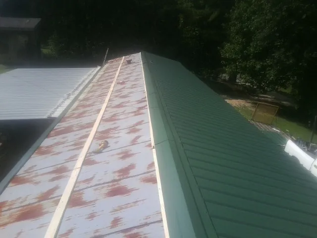 Old rusted panels beside newly installed green metal roofing — Wind Damage Roof Repair by Roofing Brothers in Carson