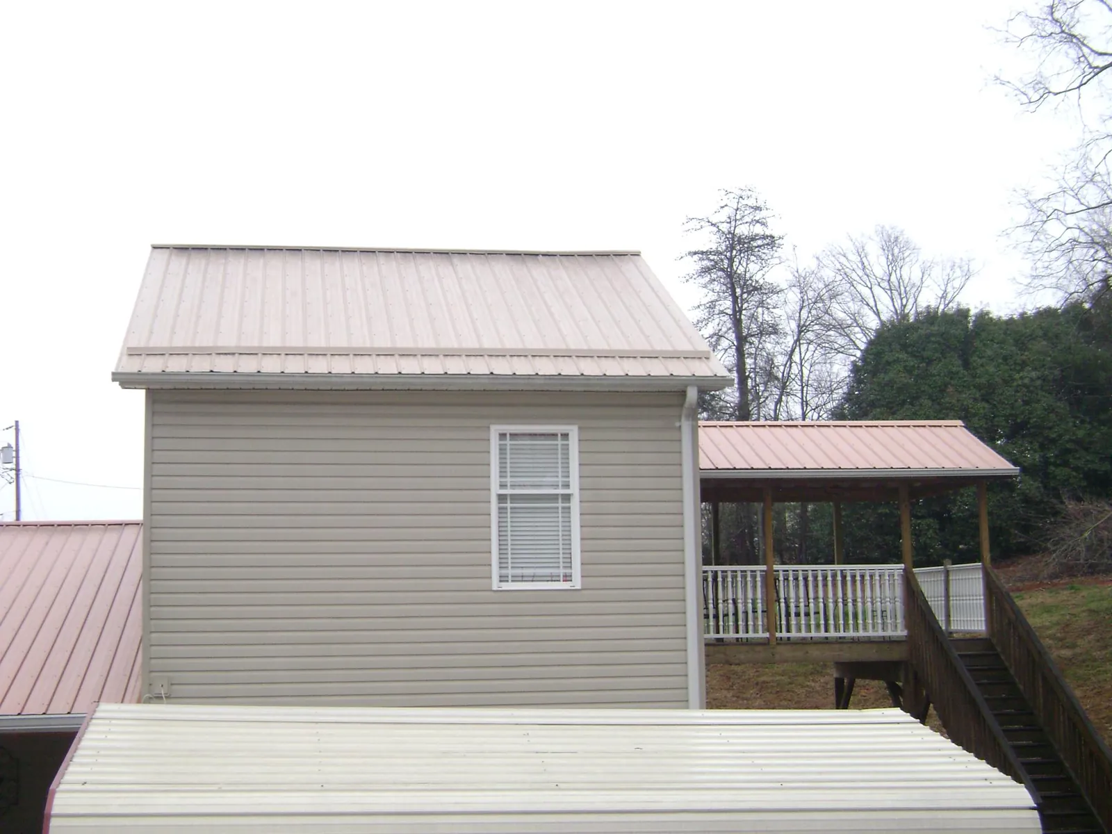 Tan metal roofs on a two story addition and attached porch, from a Roof Replacement job in Carson
