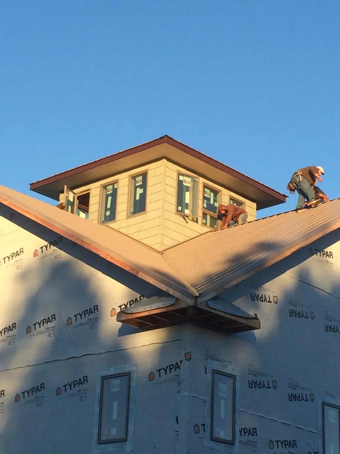 Roofers working around a rooftop cupola on a new metal roof at sunset — Roof Waterproofing in Carson by Roofing Brothers